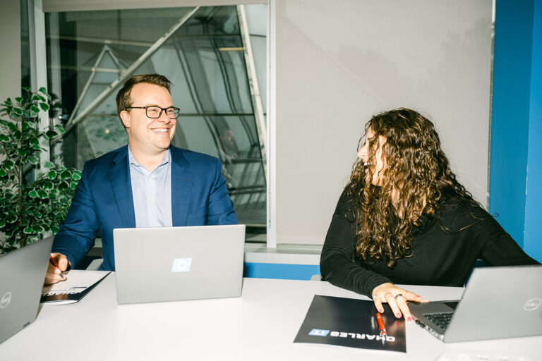 Professional man and woman in meeting laughing with computers