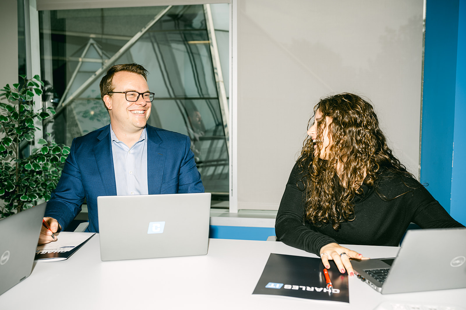 Professional man and woman in meeting laughing with computers