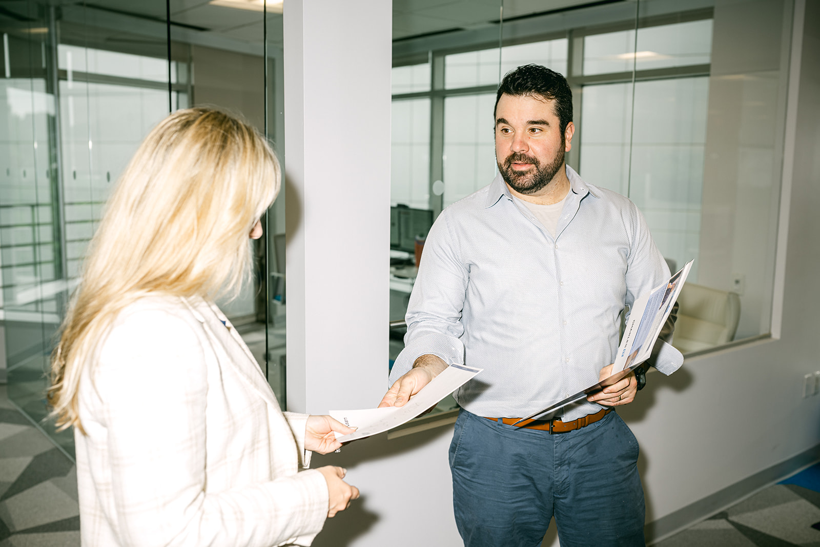 professional man handing woman paper
